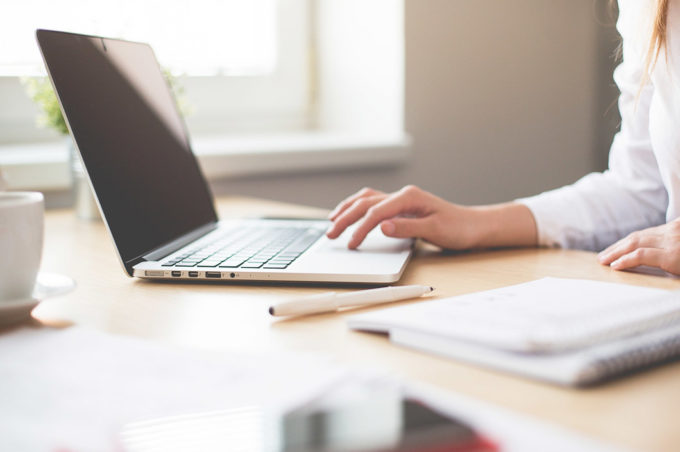 Zdjęcie dłoni kobiety pracującej na laptopie